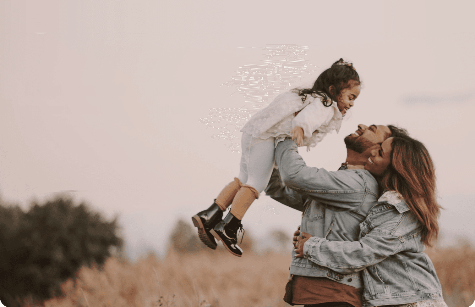 Parents lifting their child in a meadow